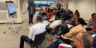 Group of staff members sitting in a semi-circle watching a presentation.