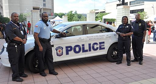 UDC police officers in front of a police cruiser