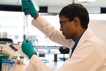 a scientist adding liquid to a test tube