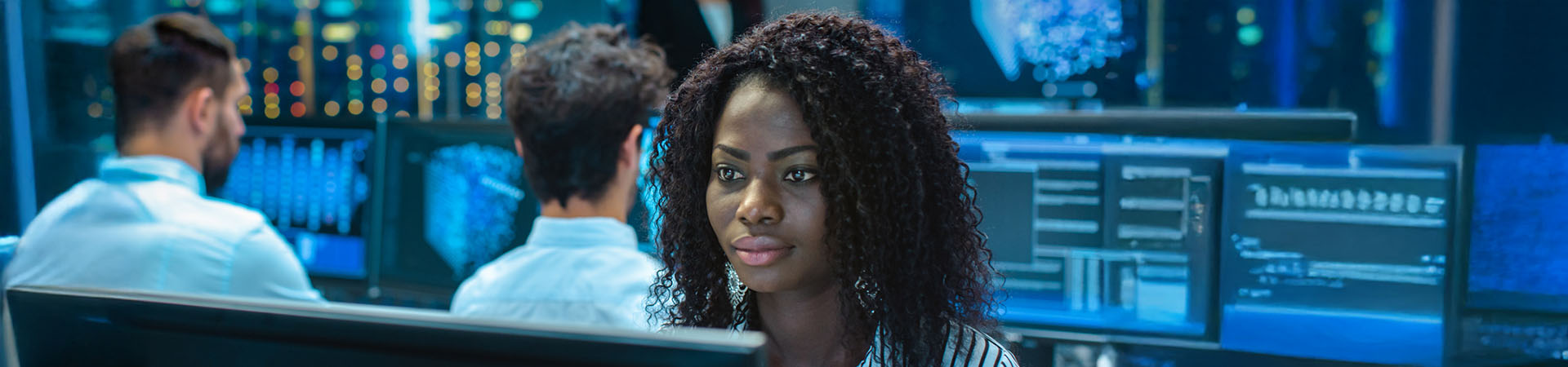 Woman working at a computer in front of a row of computer monitors