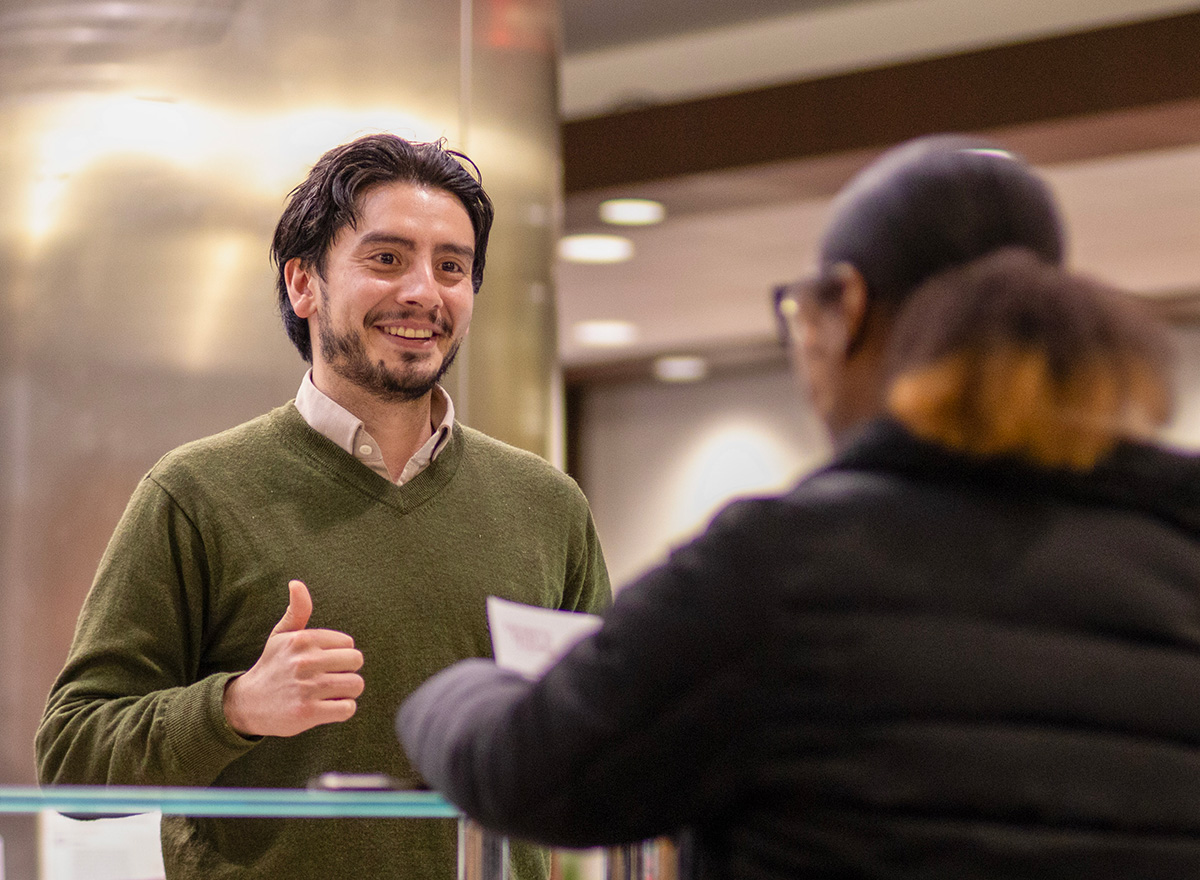 Male admission counselor assisting a visitor to the student services office.