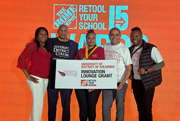 Five people standing in front of an orange Home Depot banner