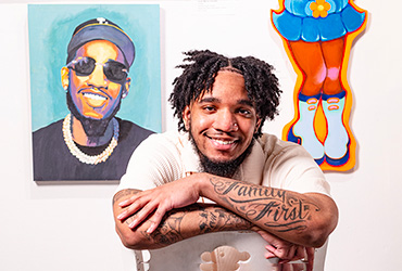 A young man sitting in a chair in front of a wall of art