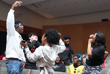 A group of people dancing in the seats of an auditorium.