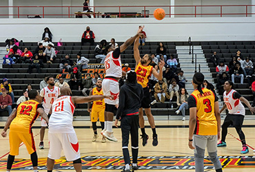 UDC alumni playing basketball in a gym.